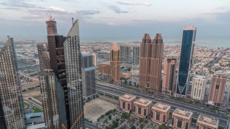 Téléchargez les photos : Bâtiments de grande hauteur sur Sheikh Zayed Road à Dubaï passage aérien de nuit au jour timelapse, EAU. gratte-ciel dans le quartier financier international d'en haut. Maisons de ville et villas en arrière-plan - en image libre de droit