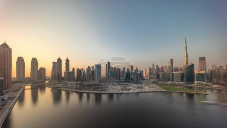 Téléchargez les photos : Paysage urbain avec les gratte-ciel de Dubai Business Bay et le canal d'eau timelapse aérien. Skyline panoramique moderne avec des tours résidentielles et de bureaux sur le front de mer. Soirée jusqu'au coucher du soleil - en image libre de droit