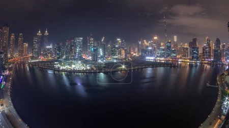 Photo for Aerial view to Dubai Business Bay and Downtown with the panoramic skyline skyscrapers and towers along waterfront on canal day to night transition timelapse. Construction site with cranes after sunset - Royalty Free Image