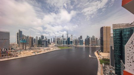 Foto de Vista panorámica aérea de Dubai Business Bay y el centro durante todo el día desde el amanecer hasta el atardecer. Varios rascacielos y torres a lo largo del paseo marítimo en el timelapse del canal. Construcción con grúas - Imagen libre de derechos