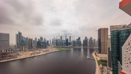 Photo for Aerial panoramic view to Dubai Business Bay and Downtown during all day from sunrise to sunset. Various skyscrapers and towers along waterfront on canal timelapse. Construction site with cranes - Royalty Free Image