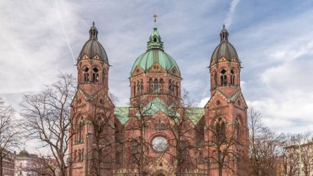 Photo for St. Luke's Church (St. Lukas or Lukaskirche) timelapse, the largest Protestant church in Munich, southern Germany. Cloudy sky and traffic on the street - Royalty Free Image
