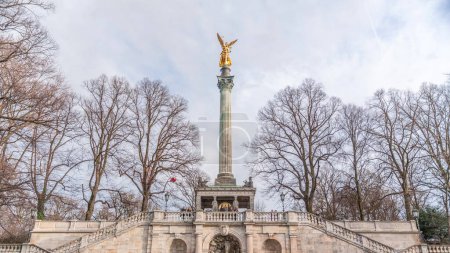 Photo for Front view of famous Peace Column with golden Angel of Peace statue (Friedensengel) timelapse, people and public park in the Bavarian capital near Isar river. Germany, Munich, Bogenhausen - Royalty Free Image