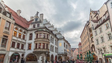 Téléchargez les photos : Paysage urbain avec des maisons de bier et des restaurants en plein air sur Platzl timelapse à Munich, Bayern, Allemagne. Zone de marche avec tables et chaises. Les gens se relaxent dans les cafés - en image libre de droit