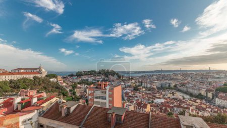 Foto de Panorama mostrando Lisboa famosa vista aérea desde Miradouro da Senhora do Monte mirador más alto de Alfama y Mauraria casco antiguo de la ciudad timelapse, 25 de abril Puente antes del atardecer. Lisboa, Portugal - Imagen libre de derechos
