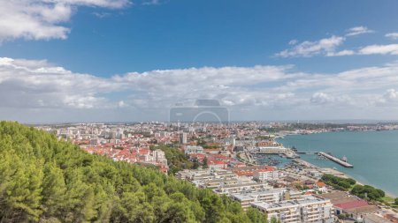 Foto de Panorama mostrando vista aérea del puerto deportivo y el timelapse del centro de la ciudad en Setúbal, Portugal. Techos rojos y paseo marítimo con barcos y barcos de arriba. Cielo nublado en el día soleado - Imagen libre de derechos