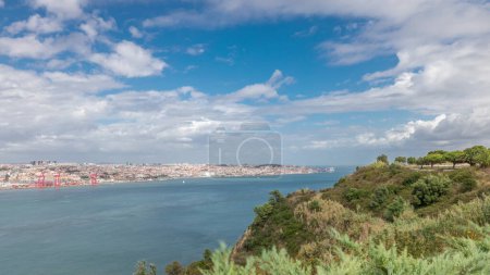 Photo for Panorama showing Lisbon cityscape and Tagus river timelapse, aerial view of Old Town Alfama with landmark suspension 25 of April bridge from viewpoint of Cristo Rei in Almada. Portugal - Royalty Free Image