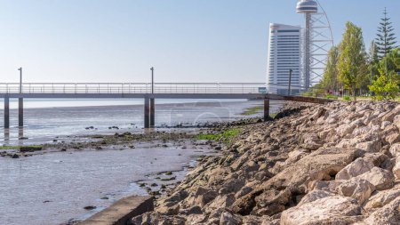 Photo for Motion from the low to high tide next to Vasco da Gama Bridge in Parque das Nacoes timelapse in Lisbon, Portugal. Level of water is rising up. Waterfront in Park of Nations district with skyscraper - Royalty Free Image