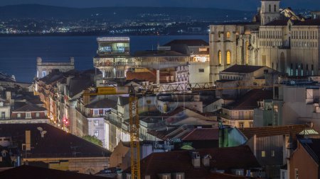 Foto de Lisboa desde arriba por la noche timelapse: vista del iluminado barrio de Baixa con ascensor de Santa Justa, también llamado Carmo Lift y Convento da Ordem do Carmo, iglesia histórica. Vista desde arriba. Portugal - Imagen libre de derechos