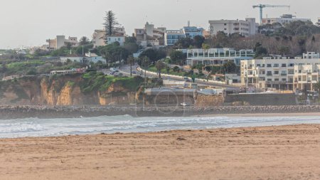 Téléchargez les photos : Vue aérienne de la belle plage de Meia Praia timelapse à Lagos, Algarve, Portugal le matin. Beaucoup de maisons sur les falaises. Vue rapprochée avec route incurvée et jetée lapidée - en image libre de droit