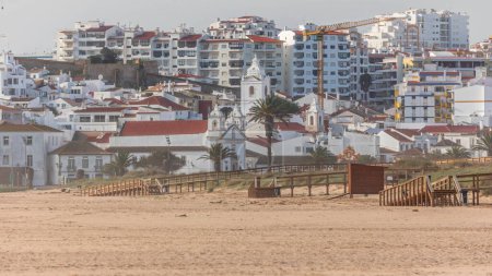 Luftaufnahme des schönen Meia Praia Strand Zeitraffer in Lagos, Algarve, Portugal am Morgen. Viele Häuser an Klippen. Nahsicht mit Kirche und Kran