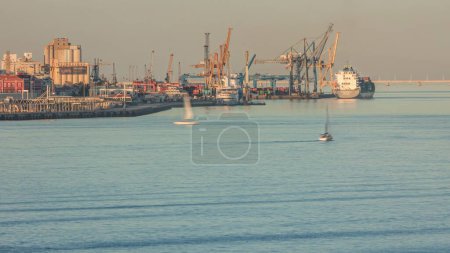 Photo for Container cargo ship during docking at industrial port with cranes aerial timelapse. Import export commercial trade business logistic and transportation. Tejo river during sunset in Lisbon, Portugal - Royalty Free Image