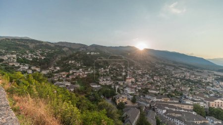 Panorama, das die Stadt Gjirokastra bei Sonnenuntergang aus der Sicht der Festung der osmanischen Burg Gjirokaster zeigt. Albanien Luftaufnahme mit untergehender Sonne