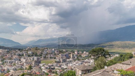Panorama zeigt die Stadt Gjirokastra vom Aussichtspunkt mit vielen typischen historischen Häusern mit steinernen Dächern aus dem Zeitraffer von Gjirokaster. Albanien Luftaufnahme des Tals mit Regenwolken und Schauerbewegung