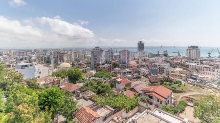 Photo for Panorama showing aerial view of city centre (old town) and the harbour of Durres timelapse from viewpoint, Albania. Many houses with red roofs and green trees from above with clouds on she sky - Royalty Free Image