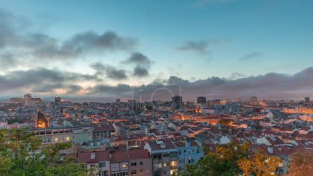 Foto de Panorama que muestra vista aérea del centro de Lisboa día a noche timelapse transición, Portugal. Techos rojos de casas típicas en el horizonte de la ciudad vieja. Barrio histórico después del atardecer en la capital - Imagen libre de derechos