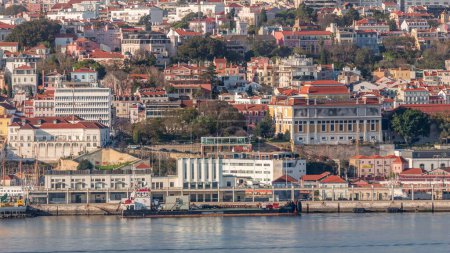 Photo for Aerial view of Lisbon with National Museum of Ancient Art at Janelas Verdes Street near viewpoint with restaurant timelapse. Cargo ship in port on Tejo river. Historic buildings on a hill. Portugal - Royalty Free Image