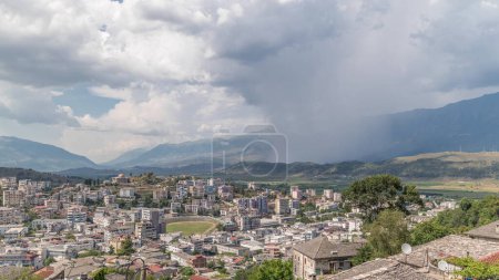 Foto de Panorama que muestra la ciudad de Gjirokastra desde el mirador con muchas casas históricas típicas con techos de piedra de Gjirokaster timelapse. Albania vista aérea al valle con nubes de lluvia y movimiento de ducha - Imagen libre de derechos