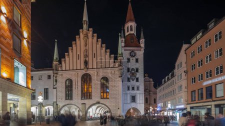 Foto de Marienplatz con el antiguo ayuntamiento de Múnich (Altes Rathaus) y el hiperlapso del timelapse nocturno de la Puerta de Talburgo, torre iluminada con reloj. Munchen-Altstadt, Baviera, Alemania. - Imagen libre de derechos