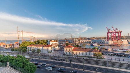 Téléchargez les photos : Panorama montrant la vue aérienne des navires au quai dans le port de la ville de Lisbonne timelapse avec le pont du 25 Avril sur le fond. Trafic sur l'avenue pendant l'heure du coucher du soleil d'en haut - en image libre de droit