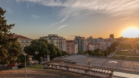 Téléchargez les photos : Panorama montrant le coucher du soleil sur la pelouse à Alameda Dom Afonso Henriques avec des bâtiments colorés et la fontaine lumineuse intemporelle aérienne. Vue d'en haut avec ciel nocturne à Lisbonne, Portugal - en image libre de droit