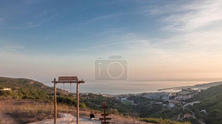 Foto de Panorama que muestra la vista aérea de la ciudad de Sesimbra y el puerto durante la puesta del sol timelapse, Portugal. Paisaje nocturno superior con castillo en la colina desde el mirador con un columpio. Resort en el distrito de Setubal - Imagen libre de derechos