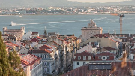 Photo for Aerial view of Lisboa downtown timelapse during sunset. Panoramic of Baixa, Rossio and Chiado red rooftops from above. Arch on the Augusta street. Almada on the other side of Tejo river. Portugal - Royalty Free Image
