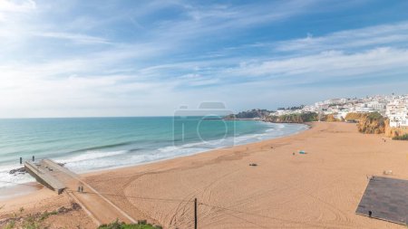 Photo for Panorama showing wide sandy beach and Atlantic ocean in city of Albufeira timelapse. White houses on the top of cliffs. Aerial view from above. Clouds on a blue sky. Algarve, Portugal - Royalty Free Image