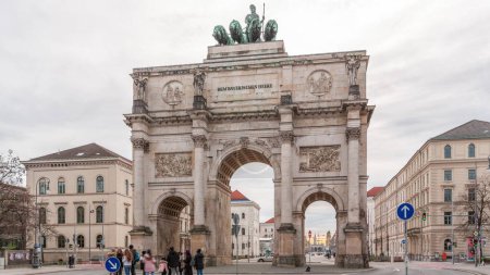 Téléchargez les photos : Le Siegestor ou Victory Gate à Munich est un arc commémoratif, couronné d'une statue de Bavière avec un lion quadriga timelapse. Trafic dans la rue autour du monument. Vue de face. Allemagne - en image libre de droit