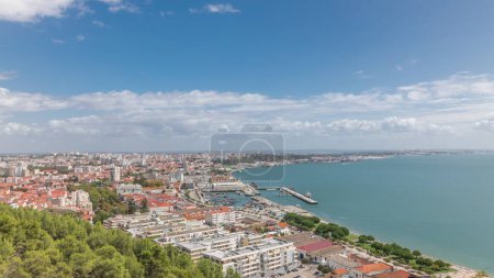 Panorama mit Luftaufnahme des Yachthafens und der Innenstadt in Setubal, Portugal. Rote Dächer und Uferpromenade mit Booten und Schiffen von oben. Bewölkter Himmel an sonnigem Tag