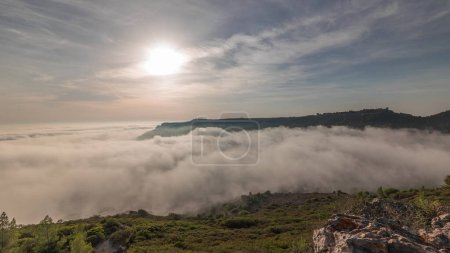 Foto de Panorama que muestra la vista aérea de la ciudad de Sesimbra y el puerto cubierto por la niebla timelapse, Portugal. Paisaje superior sobre las nubes y puesta de sol. Resort en el distrito de Setubal - Imagen libre de derechos
