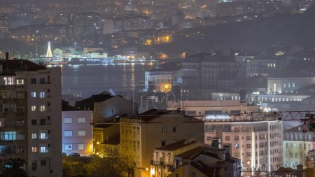 Téléchargez les photos : Vue aérienne du timelapse nocturne du centre de Lisboa. Panoramique des toits Baixa, Rossio et Chiado d'en haut. Bâtiments éclairés. Almada de l'autre côté de la rivière Tejo. Portugal - en image libre de droit