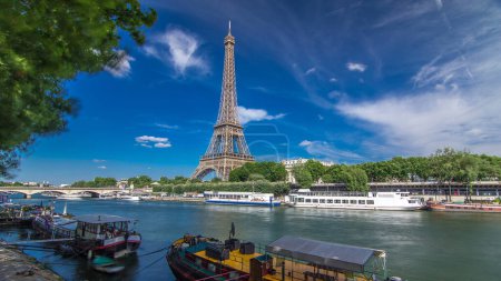 Foto de El timelapse aéreo de la torre Eiffel hiperlapso desde el paseo marítimo en el río Sena en París. Barco y barcos en el río en el soleado día de verano - Imagen libre de derechos