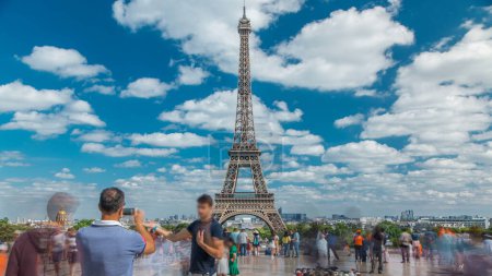 Téléchargez les photos : Les gens marchant sur la célèbre place Trocadéro avec la tour Eiffel dans le timelapse de fond. Trocadéro et tour Eiffel sont les attractions les plus visitées de Paris. Ciel bleu nuageux le jour d'été - en image libre de droit