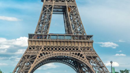 Photo for Close up view of first section of the Eiffel Tower with tourists on observation deck timelapse in Paris, France. Sunny summer day with blue clody sky - Royalty Free Image