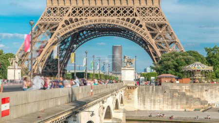 Photo for Eiffel Tower bottom part view from the Bridge of Jena timelapse, Paris, France. Blue cloudy sky at summer day and traffic on the road - Royalty Free Image