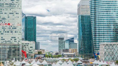Foto de Panorama de rascacielos modernos timelapse en el famoso distrito financiero y de negocios de París - La Defense. Cielo nublado en el día de verano. Arco del Triunfo visible en el horizonte. - Imagen libre de derechos