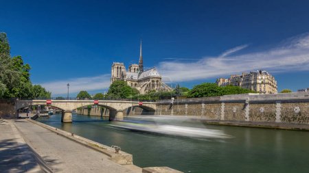Foto de Seine waterfront y Notre Dame de Paris timelapse hyperlapse es uno de los símbolos más famosos de París. Puente del Arzobispado. Vista en el soleado día de verano - Imagen libre de derechos