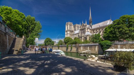 Foto de Notre Dame de Paris timelapse hyperlapse es uno de los símbolos más famosos de París. Estación de botes a la derecha. Vista desde el paseo marítimo de Siene en el soleado día de verano - Imagen libre de derechos