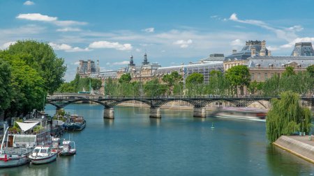Foto de Barco turístico pasa por debajo de Pont des Arts, en la estación de barcos en el río Sena timelapse frente al mar en París. París es el principal destino turístico de Europa. Cielo azul nublado en el día de verano - Imagen libre de derechos