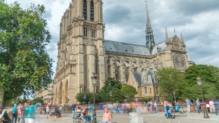 Photo for Notre-Dame de Paris timelapse. Medieval Catholic cathedral on the Cite Island in Paris, France. Side view from Double bridge before sunset. Walking tourists. Cloudy sky at summer day - Royalty Free Image