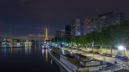Foto de La Estatua de la Libertad y la Torre Eiffel reflexionaron sobre el hiperlapso del timelapse de la noche acuática con edificios modernos y el tráfico por carretera. Vista desde el puente Mirabeau. París, Francia - Imagen libre de derechos