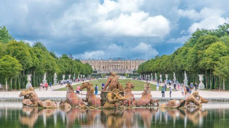 Photo for Apollo fountain in the Versailles Palace park with green lawn timelapse, Ile de France. Royal Palace on background with reflection on water. Crowd of tourists at summer day - Royalty Free Image