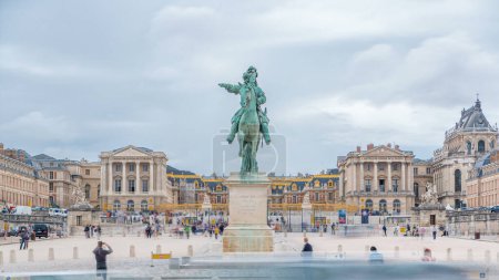 Téléchargez les photos : Terrain de parade du château de Versailles avec la statue équestre de Louis XIV vue frontale intemporelle. Trafic sur la route et les touristes se promenant. Ciel nuageux le jour d'été - en image libre de droit