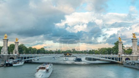 Téléchargez les photos : Pont d'Alexandre III enjambant la Seine timelapse. Décoré avec des lampes Art Nouveau et des sculptures ornées. Vue depuis le pont des Invalides avec des bateaux. Paris. La France. Ciel nuageux bleu avant le coucher du soleil - en image libre de droit