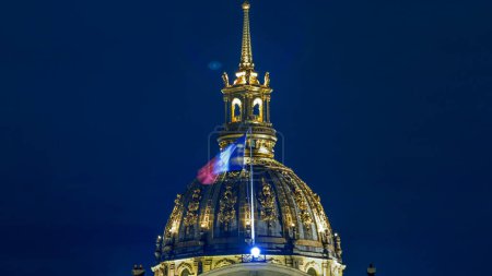Téléchargez les photos : Dôme des Invalides à l'illumination nocturne timelapse à Paris, France. Drapeau français en haut. Vue rapprochée sur le toit - en image libre de droit