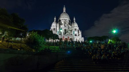 Foto de Vista frontal de Sacre coeur (Catedral del Sagrado Corazón) iluminada al atardecer hiperlapso timelapse. Mucha gente sentada en las escaleras. París, Francia - Imagen libre de derechos