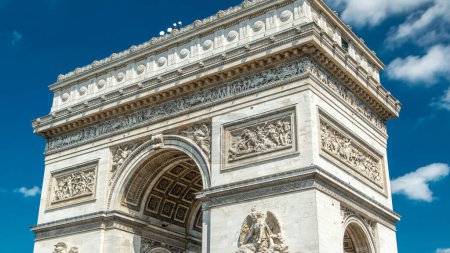 Photo for Top part of the Arc de Triomphe (Triumphal Arch of the Star) timelapse is famous monument in Paris, standing at the western end of the Champs-Elyseees. Blue cloudy sky at summer day - Royalty Free Image