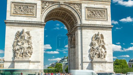 Photo for The Arc de Triomphe (Triumphal Arch of the Star) front view timelapse. Famous monument in Paris, standing at the western end of the Champs-Elyseees. Traffic on a circle road. Blue cloudy sky at summer - Royalty Free Image