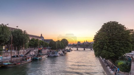 Photo for Aerial view to Pont des Arts in Paris after sunset day to night transition timelapse from Pont Neuf, France. Ship on the River Seine near square of the Vert-Galant. Reflection on water - Royalty Free Image